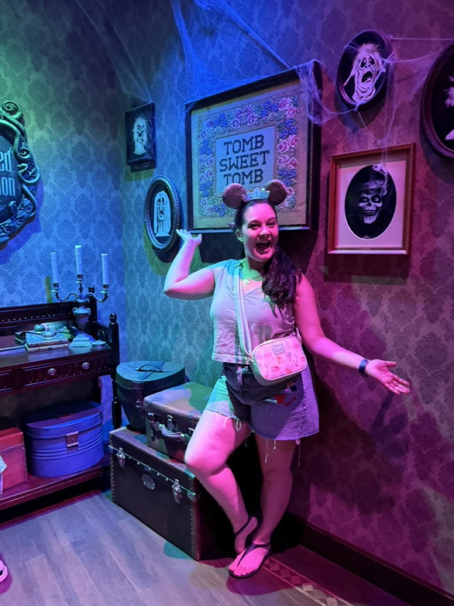 Jill posing in the Haunted Mansion queue wearing mouse ears