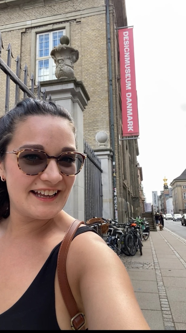 Jill outside Designmuseum Danmark in Copenhagen, the museum's red banner behind her